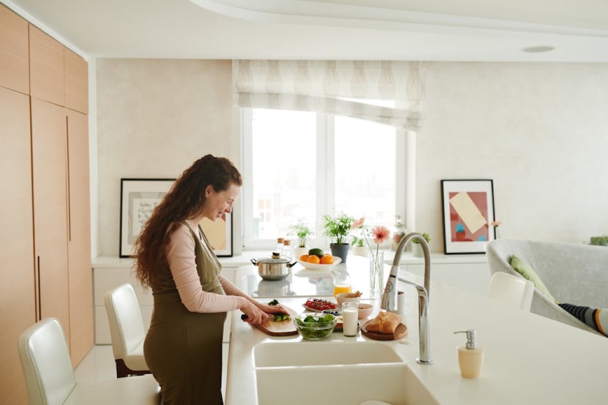 Femme enceinte sereine préparant une assiette de légumes dans sa cuisine