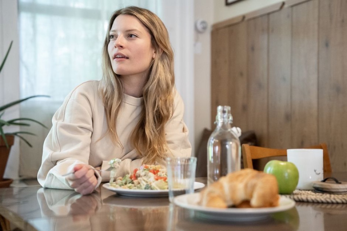 Femme assise tranquillement à table, à l'écoute de ses sensations avant de manger