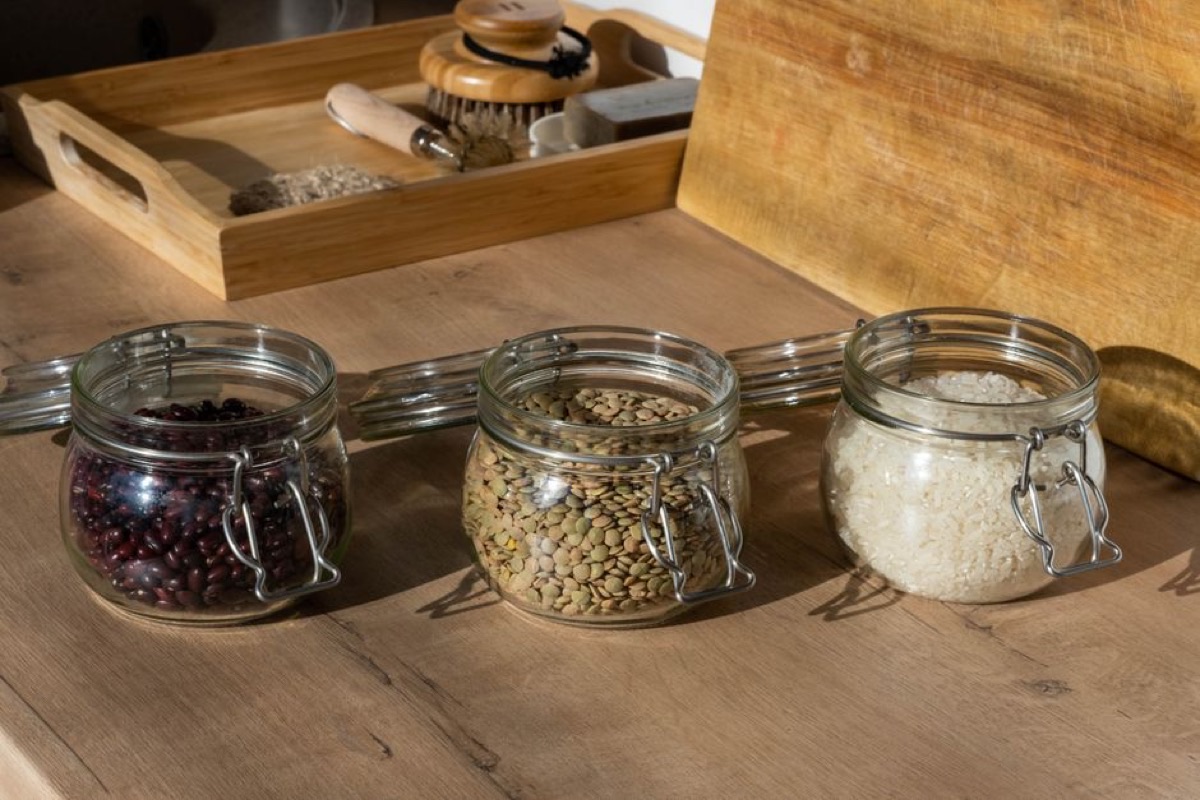 Bocaux en verre remplis de haricots, lentilles et riz posés sur une table en bois