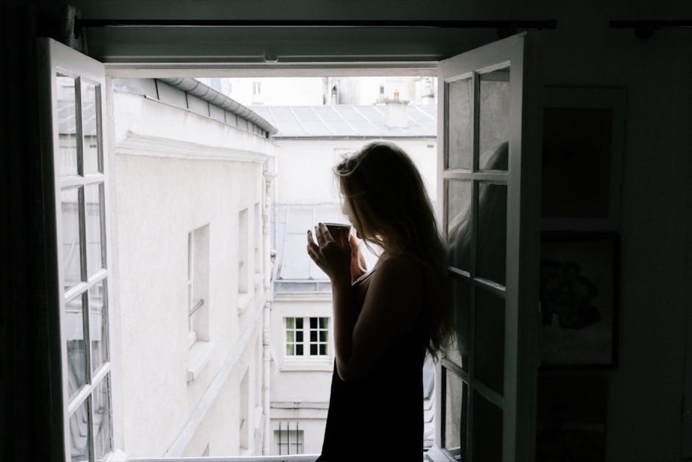 Femme en pyjama tenant une tasse, lumière du matin par la fenêtre
