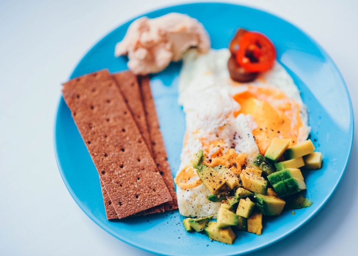 Assiette de petit-déjeuner protéiné avec œufs, avocat et toasts complets