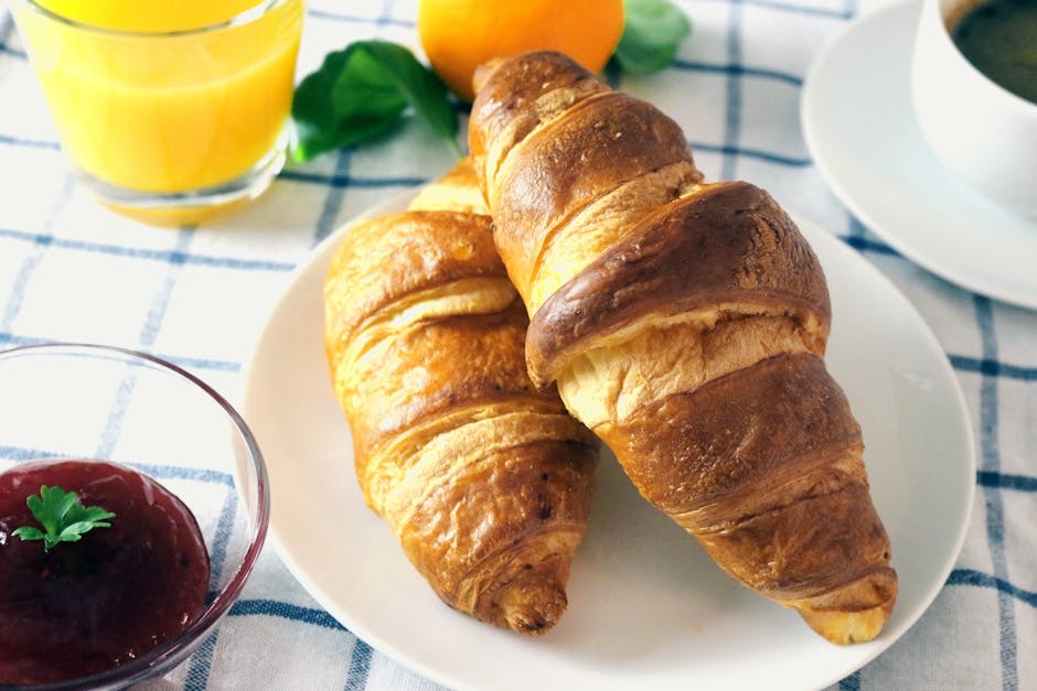 Petit-déjeuner avec viennoiseries, confiture et jus d'orange sur une table en bois