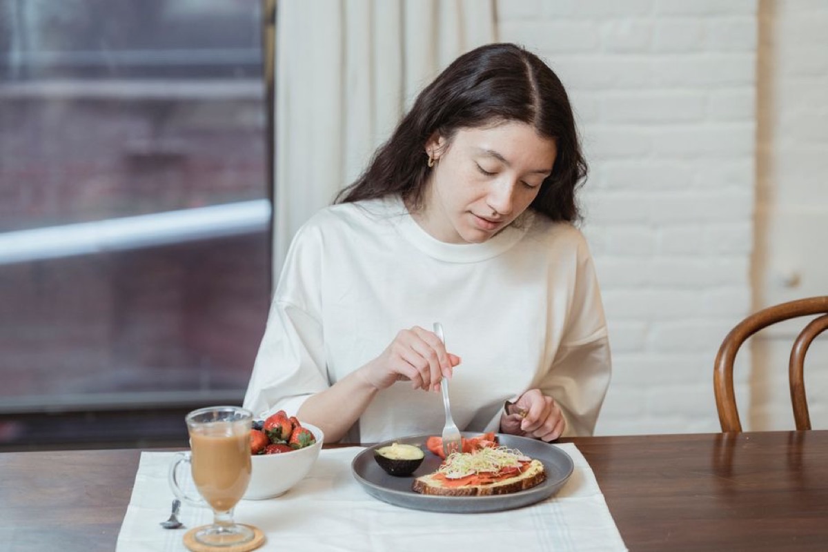 Femme attablée qui prend son petit-déjeuner tranquillement, sans écran